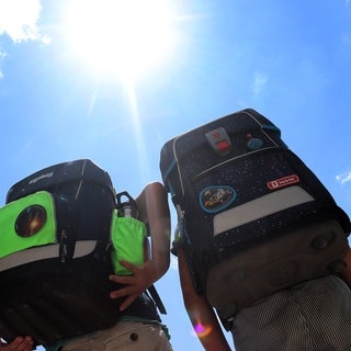 Zwei Schüler mit Ranzen in der prallen Sonne - wann gibt es hitzefrei in der Schule?