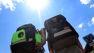 Zwei Schüler mit Ranzen in der prallen Sonne - wann gibt es hitzefrei in der Schule?