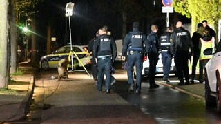 Polizisten im Dunkeln von hinten auf einer Straße in Bad Kreuznach. Viele Polizisten sind vor Ort, nachdem Schussgeräusche gemeldet wurden