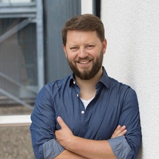 Jonathan Hadem steht im Gang eines SWR-Gebäudes.
