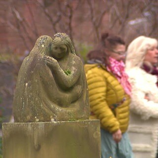 Drei Frauen laufen über einen Friedhof