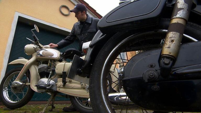 Ein Mann putzt sein altes Motorrad.