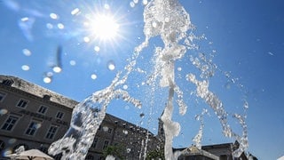 Bei hochsommerlichen Temperaturen sprudelt aus einem Brunnen Wasser in die Höhe.