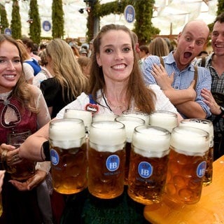 Eine Bedienung bringt im Hofbräu-Festzelt nach dem Anstich beim 190. Münchner Oktoberfest 2025 Bier zu den Gästen: Ist das jährliche Großereignis mehr als ein Massenrausch in Tracht?