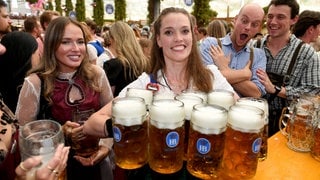 Eine Bedienung bringt im Hofbräu-Festzelt nach dem Anstich beim 190. Münchner Oktoberfest 2025 Bier zu den Gästen: Ist das jährliche Großereignis mehr als ein Massenrausch in Tracht?