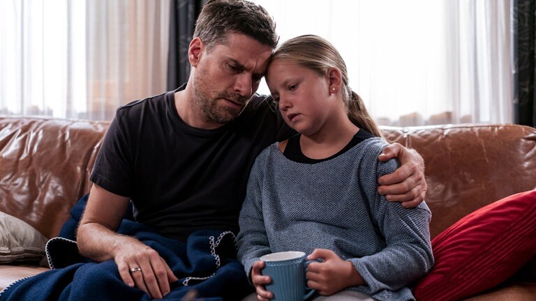 Andreas (Ralph Gassmann) hat den Arm um Carlotta (Mila Breiter) gelegt, beide sitzen auf dem Sofa