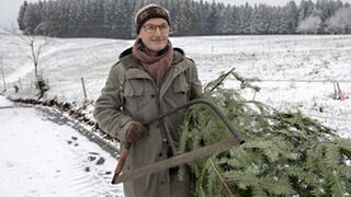 Karl hat einen Weihnachtsbaum geschlagen und trägt ihn zum Fallerhof