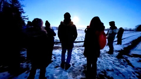 Eine Gruppe auf der hell erleuchteten, schneebedeckten Alb: Natur und Wissenswertes über die Kelten im Heidengraben bei Grabenstetten im Kreis Reutlingen. 