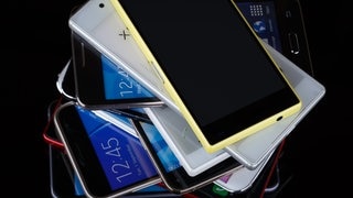 Ein Stapel mit mehreren alten Smartphones.
