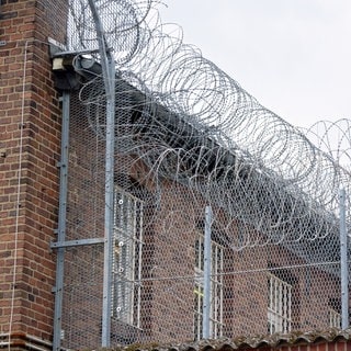 Eine Justizvollzugsanstalt mit Stacheldraht und vergitterten Fenstern.