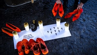Kerzen, Kreuze und Schuhe in Orange - Erinnerung an die Opfer von Femiziden