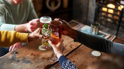 Freunde stoßen in einer Kneipe mit alkoholischen Getränken an.