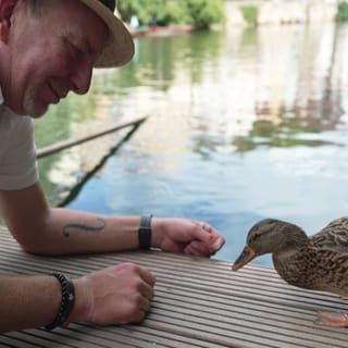 Eine Ente und ein kniender Mann auf einem Floss 