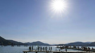 Menschen baden bei sommerlichen Temperaturen in einem See.