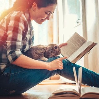 Junge Frau sitzend mit Kaninchen und Buch, lesenswert Magazin 29.03.2026