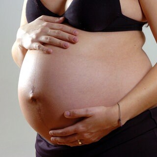 Eine Schwangere brau hält ihren Bauch. Eine neue Studie hat nun ein Signal zum Start der Geburt entdeckt.