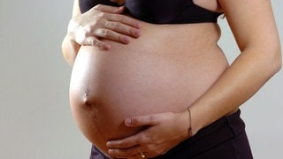 Eine Schwangere brau hält ihren Bauch. Eine neue Studie hat nun ein Signal zum Start der Geburt entdeckt.