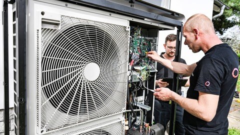 Techniker warten eine Wärmepumpe an einem Einfamilienhaus