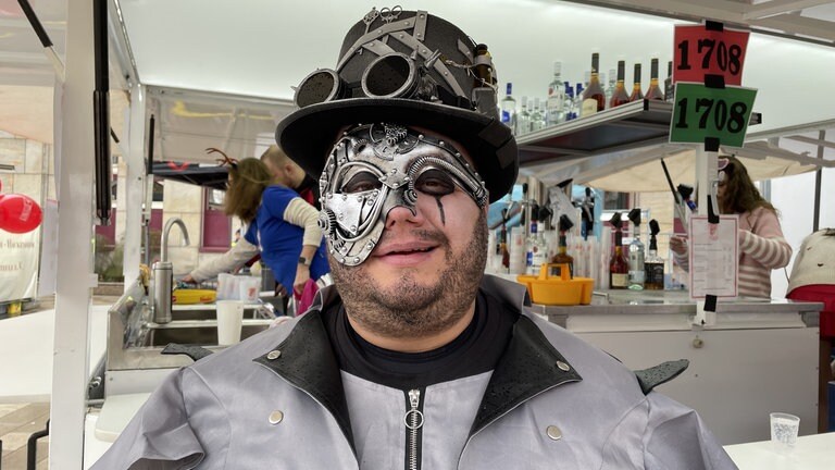 Ein Steam Punk-Fan mit viel Metall im Gesicht, der auch an einem der Stände arbeitet. Hoffentlich sieht er, was er einschenkt!