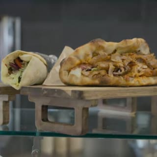 Auf einem Holzbrett sind ein Döner und ein Dürüm angerichtet. 
