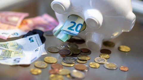 Geld wird aus dem Bauch eines Sparschweins entnommen. Ein Symbol für die Einigung der grün-schwarzen Landesregierung auf einen Nachtragshaushalt.