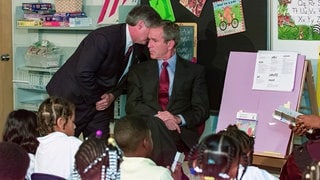 George W. Bush erfährt beim Besuch der Grundschule in SarasotaFlorida von den Anschlägen auf das World Trade Center in New York: Sein Stabschef Andy Card flüster dem Präsidenten ins Ohr: "America is under attack" – "Amerika wird angegriffen"