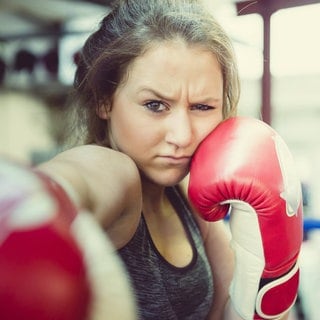 Ein Mädchen boxt mit grimmigem Gesichtsausdruck: Es gibt zahlreiche Beispiele für sexualisierte Gewalt im Sport. Betroffene fühlen sich gedemütigt oder erniedrigt. Fachleute erforschen das Ausmaß der sexualisierten Gewalt im Sport und welche Faktoren sie begünstigen. 