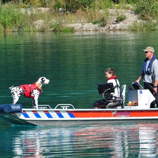 Samara Jones und ihr Rettungshund Mailo auf einem Boot. Der Dalmatiner und die 2 Personen auf dem Bild tragen Rettungswesten. 