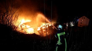 Ein Feuerwehrmann löscht das Feuer in einer Schonacher Schreinerei. 