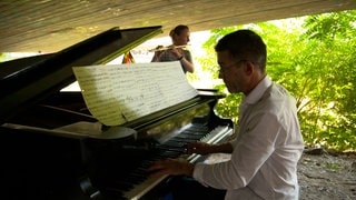 Johannes Büttner spielt auf einem Flügel unter der Obdachlosenbrücke.