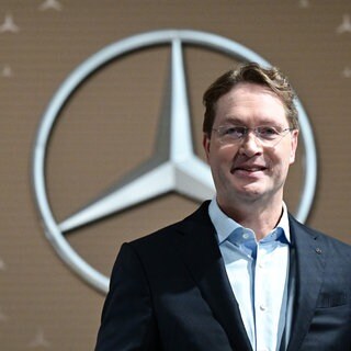 Ola Källenius, Vorstandsvorsitzender der Mercedes-Benz Group AG, steht vor der Bilanz-Pressekonferenz vor einem Mercedes-Benz Markenlogo.