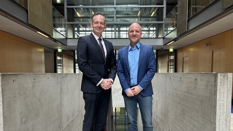 Volker Wissing und Korrespondent Jan Zimmermann stehen in der Halle im ARD-Hauptstadtstudio nebeneinander und schauen in die Kamera