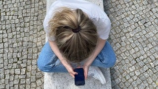 Draufblick: Mädchen schaut auf Smartphone.