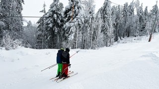 Zwei Skifahrer in einem Schlepplift im Schwarzwald.