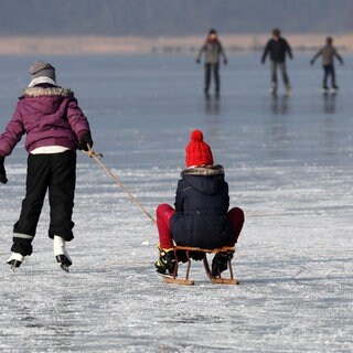Mit Schlitten und Schlittschuhen auf einem gefrorenen See (Symbolbild). Die Gemeinden in der Region warnen davor - noch ist das Eis nicht dick genug.