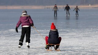 Mit Schlitten und Schlittschuhen auf einem gefrorenen See (Symbolbild). Die Gemeinden in der Region warnen davor - noch ist das Eis nicht dick genug.