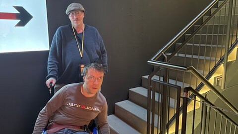 Zur unteren Etage führt nur eine Treppe - ein Aufzug fehlt. Menschen im Rollstuhl müssen den gesamten Weg gegen den Besucherstrom zurückgehen, um den Aufzug im Treppenhaus zu nutzen.