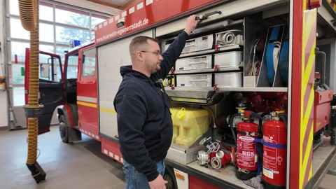 Christian vor einem Feuerwehrauto. Er engagiert sich ehrenamtlich bei der Freiwilligen Feuerwehr in Vendersheim.