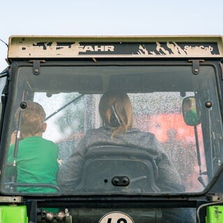 Eine Landwirtin und ihr kleiner Sohn fahren in ihrem Trecker: Die Herausforderungen für Frauen auf Höfen sind enorm: Sie müssen die harte landwirtschaftliche Arbeit erledigen, Kinder erziehen, ältere Angehörige pflegen, Generationenkonflikte bewältigen. 