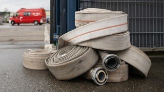 Feuerwehrschläuche liegen vor dem Tor des Entsorgungsbetriebs in Villingen-Schwenningen, wo es am Morgen gebrannt hat. 