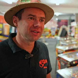 Mann steht vor Pinball-Maschinen.