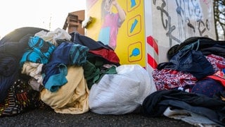 Gebrauchte Kleidungsstücke liegen vor einem Sammelcontainer für Altkleider (zu dpa: «Deutlich mehr Textilabfälle in Deutschland»)