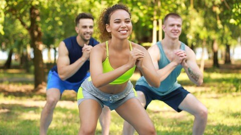 Eine Gruppe junger, sportlicher Menschen, die gemeinsam im Freien trainieren 