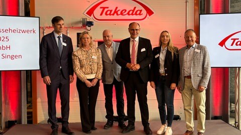 Personen stehen vor dem Biomasseheizwerk des Pharmaunternehmens Takeda in Singen.