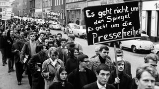 Auf dem Plakat einer Gruppe von Demonstranten steht: "Es geht nicht um den "Spiegel". Es geht um die Pressefreiheit" – In München demonstrierten am 2.11.1962 Studenten gegen die jüngsten Polizei-Maßnahmen in der Hamburger "Spiegel"-Redaktion. Etwa 300 Teilnehmer maschierten mit Spruchtafeln von der Universität zum Königsplatz, wo ein Sprecher die Forderung der Studenten nach Pressefreiheit unterstrich. Im Zuge der "Spiegel"-Affäre mussten sich Mitarbeiter des Nachrichtenmagazins "Spiegel" wegen eines kritischen Artikels gegen eine Anklage des Landesverrats zur Wehr setzen.
