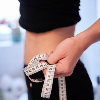 Eine Frau hält ein Zentimetermaßband an ihren Bauch. Das Pfalzklinikum behandelt immer mehr Mädchen mit Essstörungen - auch ambulant. 