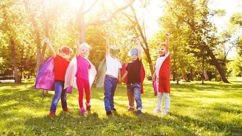 Kinder in Helden-Kostümen spielen draußen. Habt ihr auch kinderfreundliche Orte, die ihr teilen möchtet? Jetzt mitmachen bei #unsereKinder!