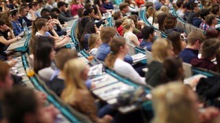 Studenten sitzen in einem Hörsaal (Symbolbild). Gerade zum Semesterstart ist in vielen Städten günstiger Wohnraum rar.