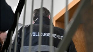 Mitarbeiter vom Vollzugsdienst stehen vor einer Wohnungstür