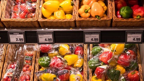 In Plastik verpackte Paprika liegen in einem Supermarkt neben losen Paprika zum Verkauf aus. 